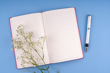 Top view of notepad and pen on blue background