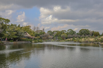 March 24 2025 Serene Lakeside Scene with Reflections and Lush Garden, Japan