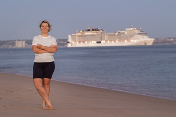 Tourist watching cruise ship leaving from beach at sunset