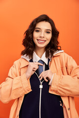 Charming portrayal of a young woman in stylish attire against a vibrant orange backdrop