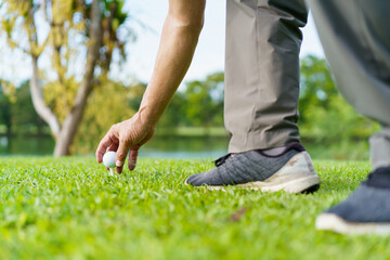 Elderly Asian man enjoying the morning round of golf in soft and warm sunlight.