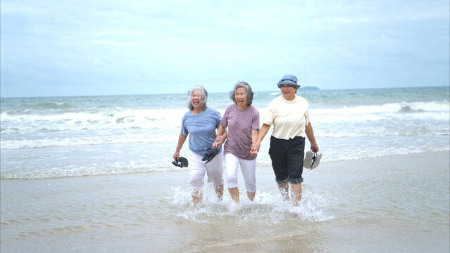 Happy senior women enjoying a playful walk on the beach