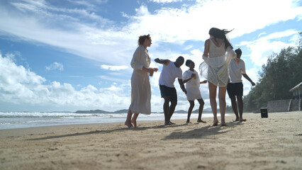 Group of diverse friends having fun at the beach, drink and dance in the waves