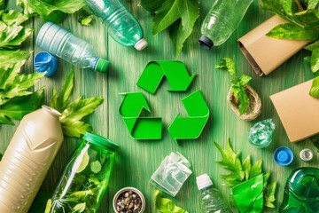 Recycling concept with plastic bottles and green plants on wooden surface