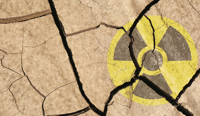 Yellow radioactive sign on cracked dry earth, top view. Radiological pollution