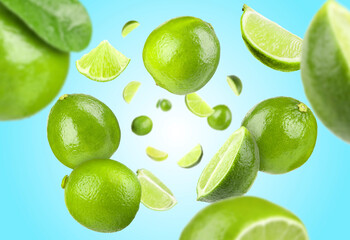 Fresh limes swirling in air against light blue background