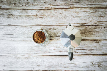 Minimal top-view of moka pot halves: one packed with fresh grounds, the other closed and ready to brew, with generous copy space on pale wooden background for modern cafe ads