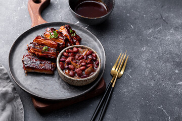 Roasted Pork Ribs in BBQ Sauce with Red Beans in the plate and grey background