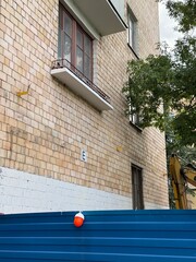 Facade of a Soviet-style residential building with brickwork, barred window, and demolition fencing. Urban decay and renovation concept. Ideal for illustrating public housing, construction