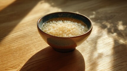 Light-colored grains in a dark-blue bowl on a light-wood surface