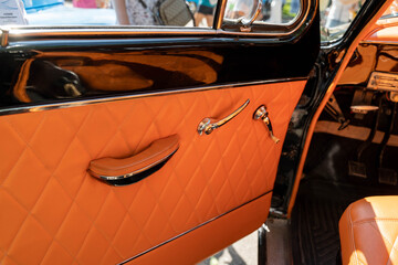 Orange leather interior and chrome door handle of classic car
