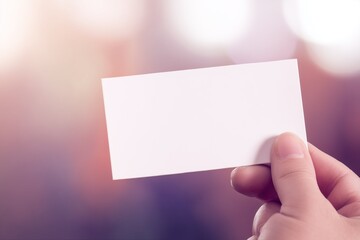 Obraz premium Hand holding blank white ticket mockup with soft bokeh background - perfect template for event passes, vouchers, business cards, and promotional materials