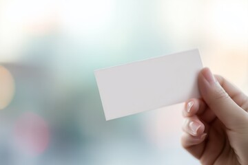 Hand holding blank white ticket mockup with soft bokeh background - perfect template for event passes, vouchers, business cards, and promotional materials