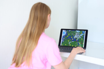 Weather app on laptop screen, sunshine, temperature, cloud coverage, global climate info.