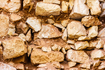 Close-Up of Natural Stone Wall with Uneven Rocks and Clay Texture