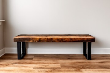 A rustic wooden bench with metal legs sits on a wooden floor against a plain white wall in a minimalist room