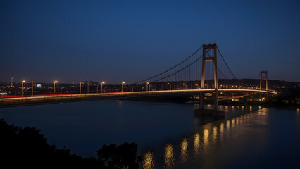 Naklejka premium The bay bridge is lit up at dusk with calm waters