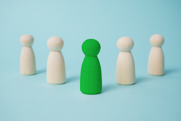 Green leads others from other wooden dolls on blue background.