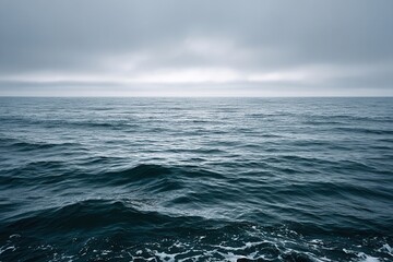 Fototapeta premium Vast open ocean under cloudy sky with gentle waves.
