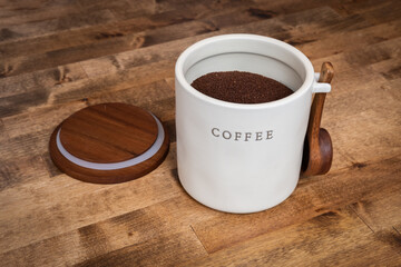 Ground Coffee in Ceramic Storage Container with Wooden Spoon on Rustic Table