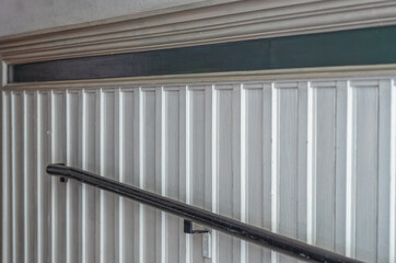 White Wood Panel Walls with a Green Band and a Black Hardwood Bannister.