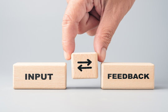 Wooden blocks illustrating the loop between input and feedback, emphasizing communication, improvement, and interactive processes in work or learning environments