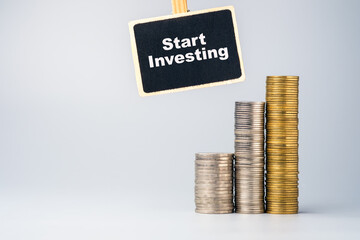 Stacked coins with a sign encouraging investment, representing financial growth, smart planning, and the beginning of a journey toward wealth and stability
