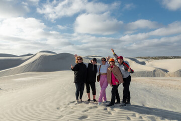 Tourists waving joyfully atop white sand dunes in baja california, capturing sunny desert landscape...