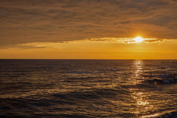 Golden sunset over calm ocean with pier silhouette
