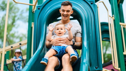 father with child boy is sitting on the slide with it