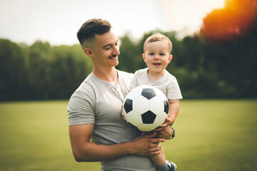 Young father with his little son playing football on football pitch
