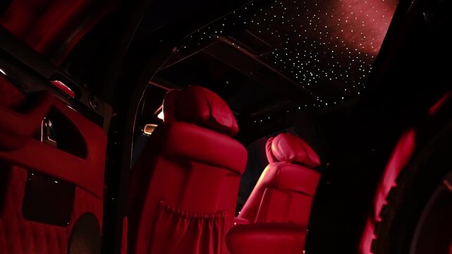 Luxurious car interior featuring plush red leather seats, illuminated with ambient lighting, showcasing a starry ceiling design, creating an opulent and inviting atmosphere for passengers