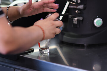 Barista Preparing a Coffee Drink Pouring Hot Milk into a Shot Glass with Espresso