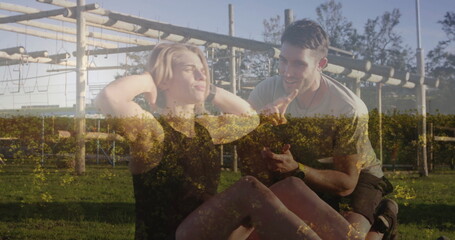 Woman performing abdominal crunches in black workout clothes at park with trainer holding ball