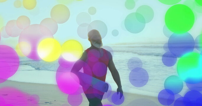 Walking African American man carrying rolled yoga mat on beach at dawn, with colored circle overlay