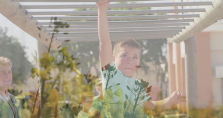 Boy swinging from monkey bars in playground, with coach wearing whistle lanyard, foliage, columns