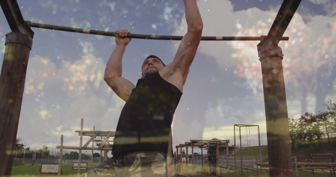 Gripping pull-up bar, fit man pulling body upward at fitness park, wearing camouflage shorts