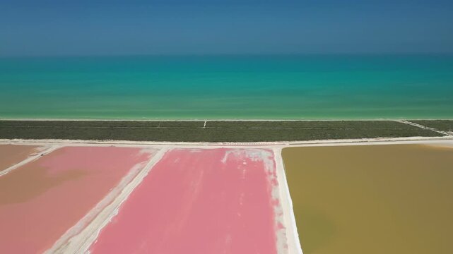 Stunning aerial view of the pink salt evaporation ponds in Las Coloradas, Mexico, contrasting with the turquoise Caribbean Sea