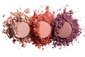 Three eyeshadow palettes, various shades of light peach, coral, and mauve, are scattered in a pile of loose powder