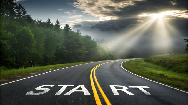 The word start painted on a winding road leading into a misty forest with sunbeams