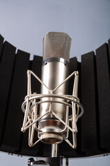Silver studio microphone with a holder on a gray background