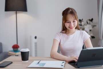 Smiling asian businesswoman using tablet and analyzing financial charts while working remotely from...