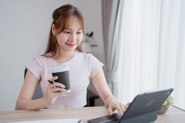 Freelancer working from home, using a tablet while enjoying a cup of coffee. Sitting comfortably at...