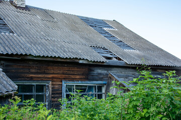 Dilapidated wooden house with damaged roof and overgrown garden symbolizing decay and abandonment