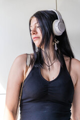 Young woman listening to music with wireless headphones and cross necklace