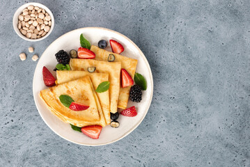Thin lupine flour pancakes with fresh berries on blue background. Gluten free dessert. Top view. 