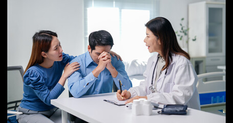 A woman and a man are sitting at a table with a doctor