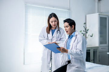 Two doctors are sitting on a bed, looking at a clipboard