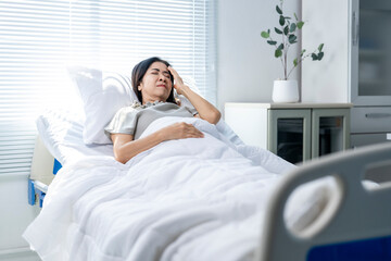 A woman in a hospital bed with a pained expression on her face
