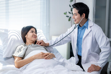 A man in a white coat is checking a woman's heart